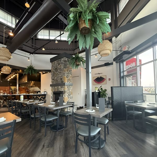Interior of Soi21 Asian Bistro & Bar with tables, chairs, a stone fireplace, and open kitchen.