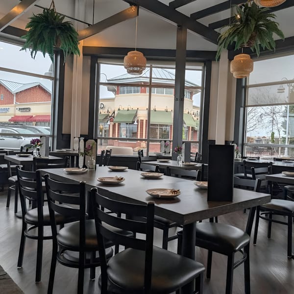Interior of Soi21 Asian Bistro & Bar, featuring dining tables, chairs, and large windows overlooking a street.