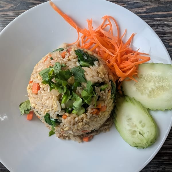 Soi21 Asian Bistro & Bar's fried rice with cilantro, carrots, and cucumber slices on a white plate.