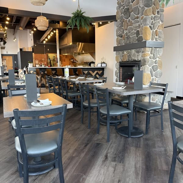 Interior of Soi21 Asian Bistro & Bar, featuring dining tables, a stone fireplace, and a bar area.